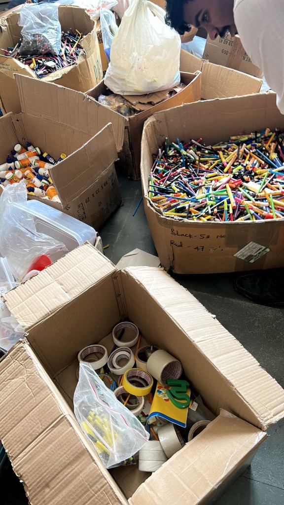 Boxes of school supplies, markers, glue, and tape, sorted and counted for delivery